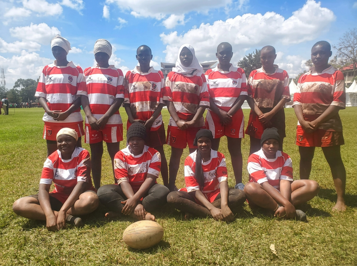 The KGSA girls rugby team in red and white jerseys posing on the pitch